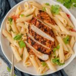 Blackened Chicken with dry rub spices charred on top of a bed of penne pasta in a bowl with olive oil, parmesan cheese and tomatoes #blackenedchicken #cajunchicken