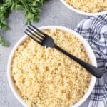 Creamy garlic Parmesan orzo in a white bowl with a black serving fork.