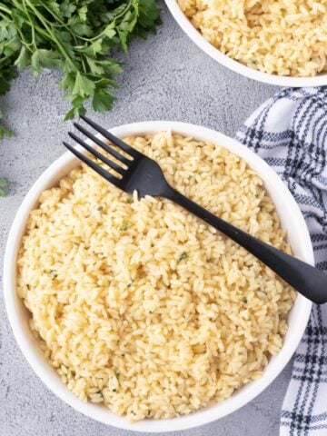 Creamy garlic Parmesan orzo in a white bowl with a black serving fork.