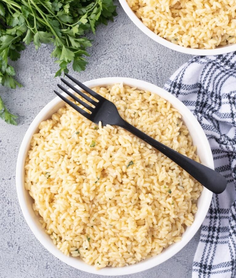 Creamy garlic Parmesan orzo in a white bowl with a black serving fork.