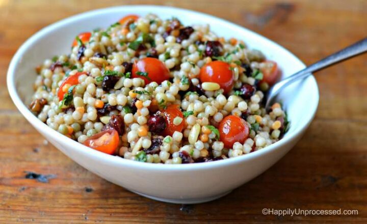 White bowl filled with Israeli couscous, diced cherry tomatoes