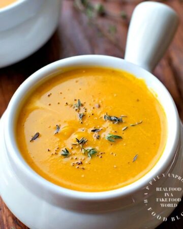 white bowl filled with roasted butternut squash sweet potato carrot soup topped with chives