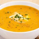 bowl of butternut-squash-sweet-potato-carrot-soup with croutons on top