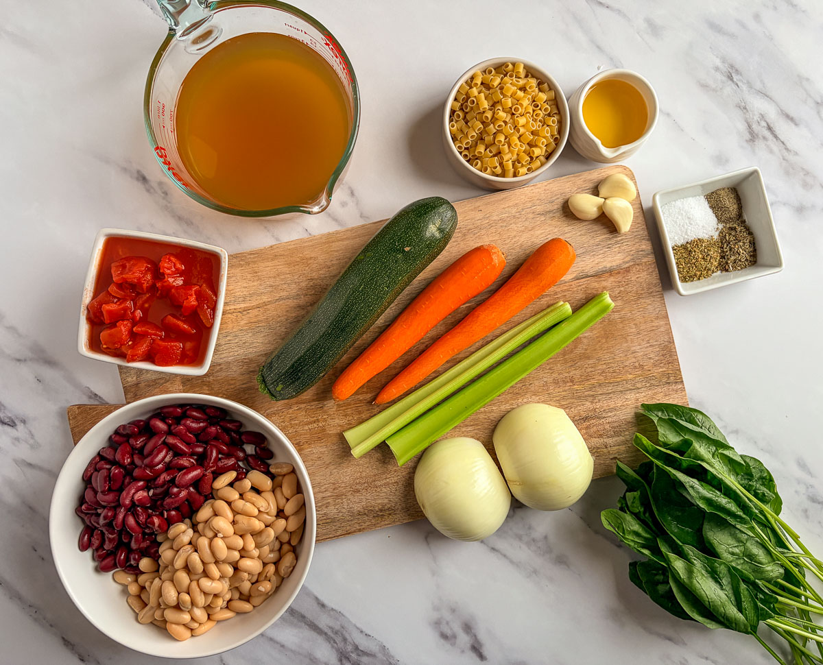 Minestrone soup ingredients on a countertop and cutting board