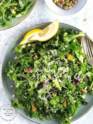 An easy lemony garlic kale salad with pistachios, pine nuts, dried cranberries topped with shaved parmesan cheese #newyearsresolution #kale #salad #healthy #happilyunprocessed