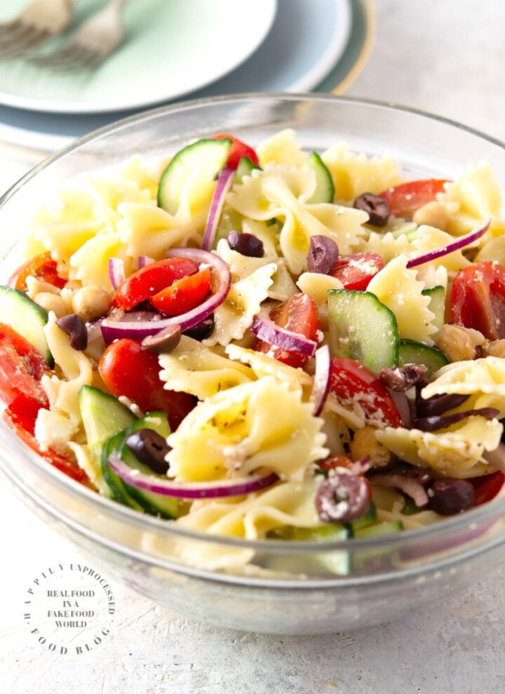 MEDITERRANEAN PASTA SALAD with bowtie pasta, red onion, cucumbers, cherry tomatoes, chick peas and feta cheese in a lemony vinaigrette #pastasalad #summer #sidedish #healthysidedish #happilyunprocessed