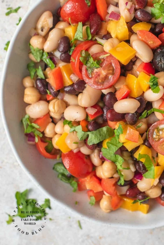 VIBRANT SUMMER 4 BEAN SALAD - 4 types of beans, colorful peppers, tomatoes, olives and red onion in a emulsified oil and vinegar dressing #summerrecipes #beansalad #potluck #healthy #summer #salads #happilyunprocessed