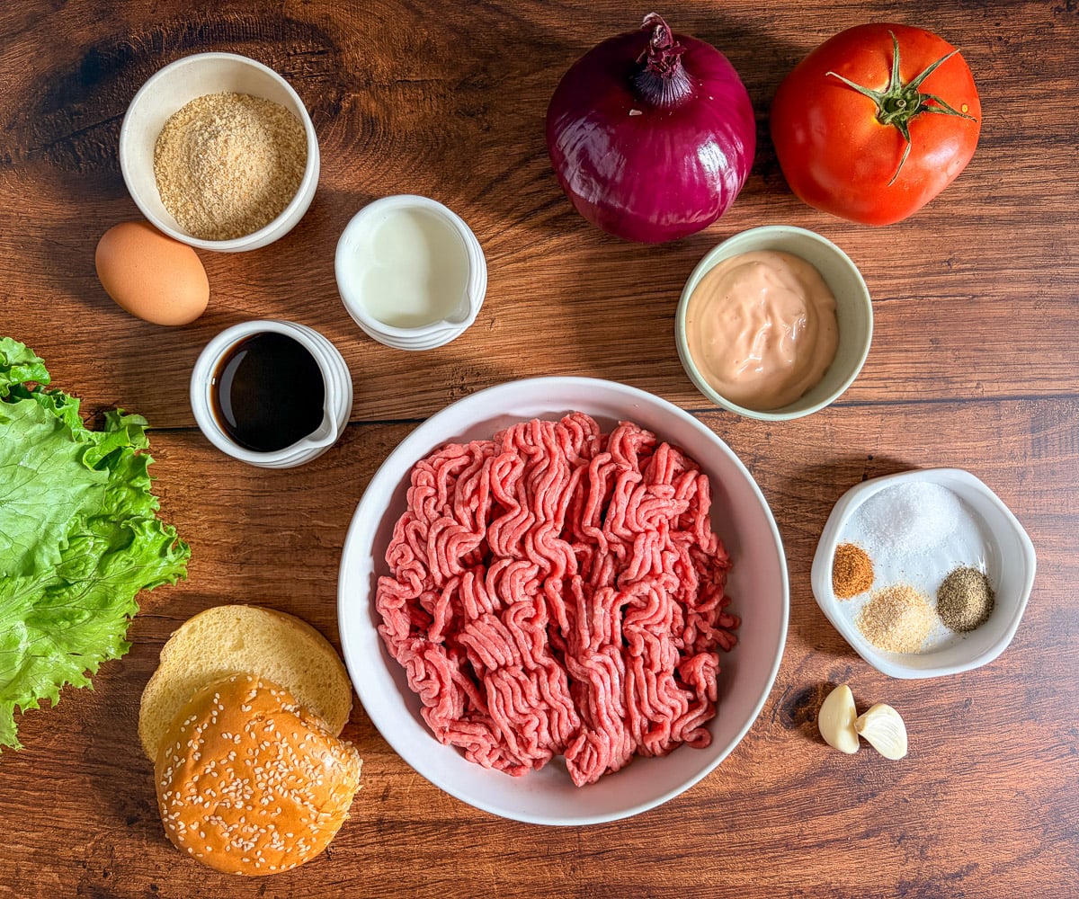 Raw ingredients needed to make juicy hamburger, on a table, in bowls