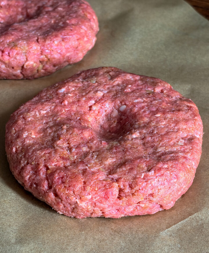 shaped burger patty with indention in center on parchment paper