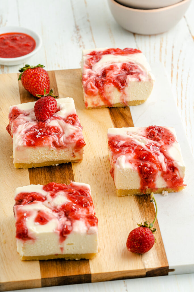 NO-BAKE-KETO-FRIENDLY-STRAWBERRY-CHEESECAKE-BARS-CUT-IN-SQUARES-ON-A-CUTTING-BOARD
