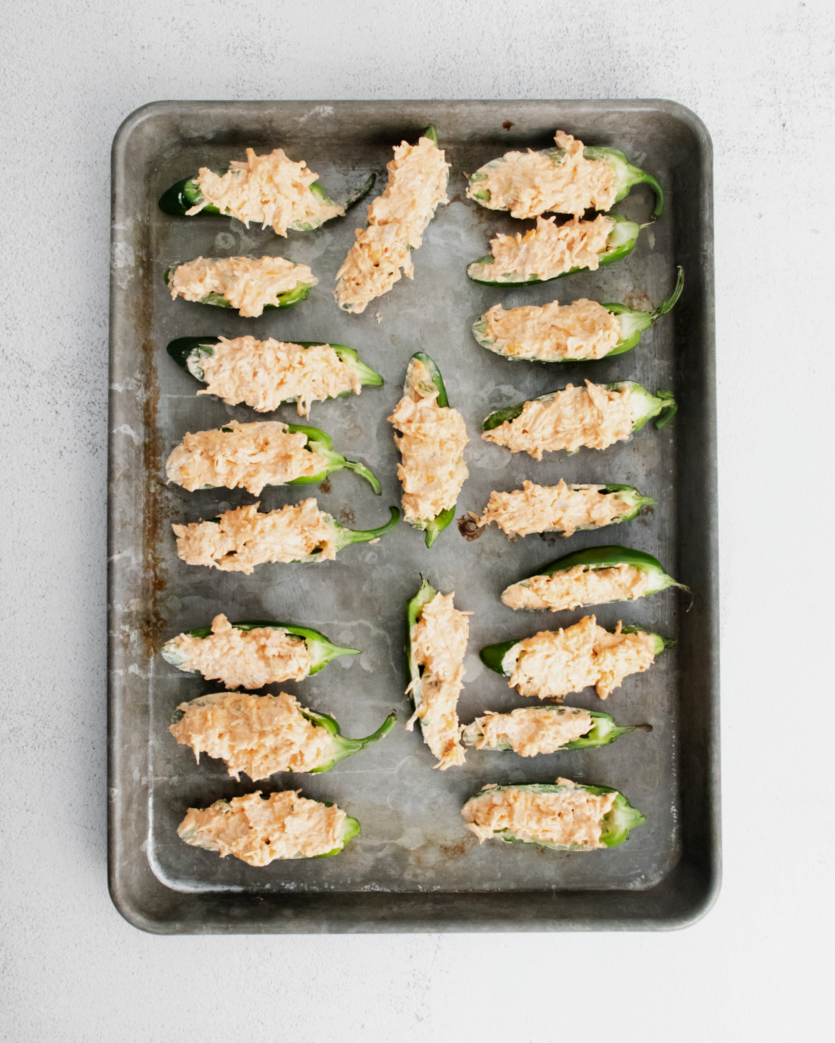 Buffalo chicken jalapeno poppers on a baking sheet ready to be baked