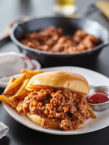 sloppy joe sandwich piled high on a toast bun with ground beef pepper and onions in a tomato sauce