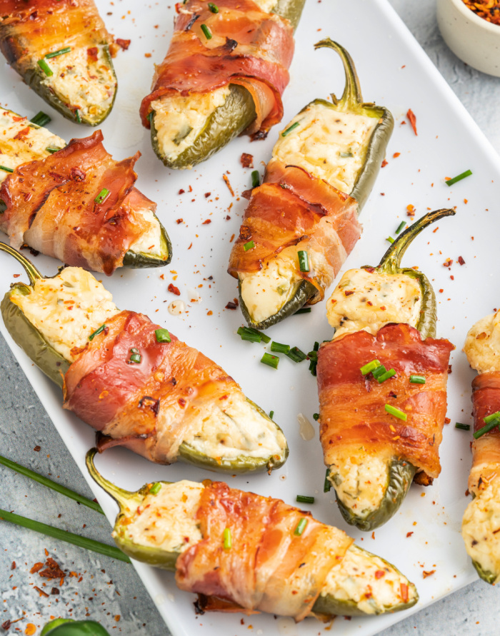 a plate of garlic and chive herbed cream cheese jalapeno poppers wrapped in bacon on a plate feature