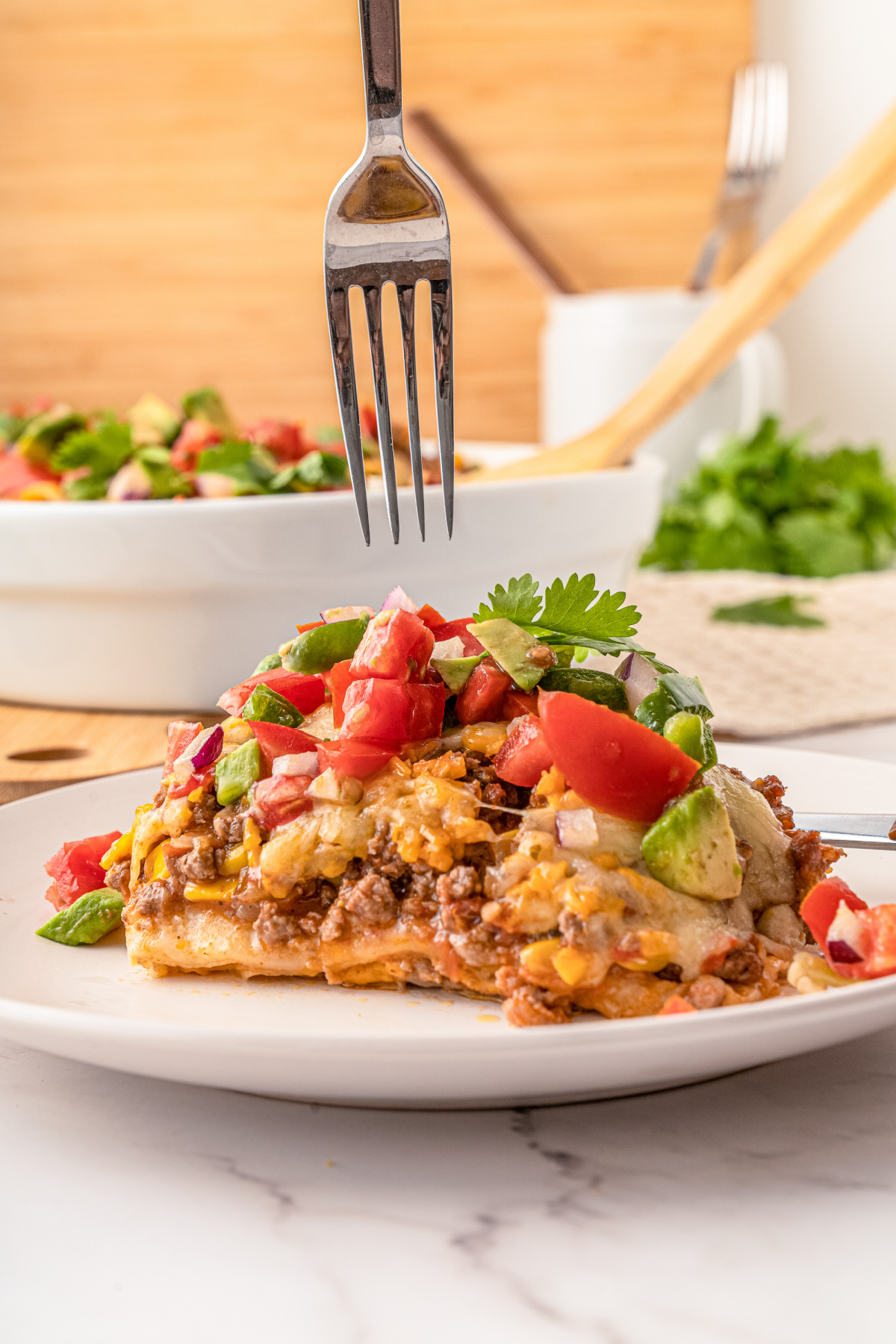 Layered Mexican Taco Lasagna Casserole with ground beef, beans, tomatoes and cheese, avocado, sour cream and lettuce