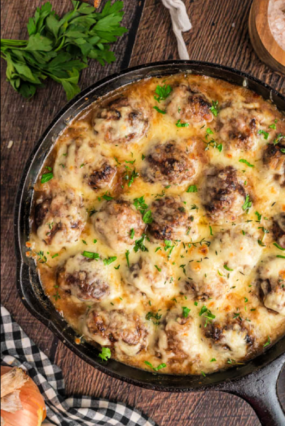 Baked French Onion Meatballs in a cast iron skillet topped with melted gooey cheese and fresh thyme