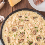 Large skillet of mushroom risotto with chunks of chicken