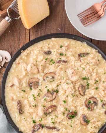 Large skillet of mushroom risotto with chunks of chicken