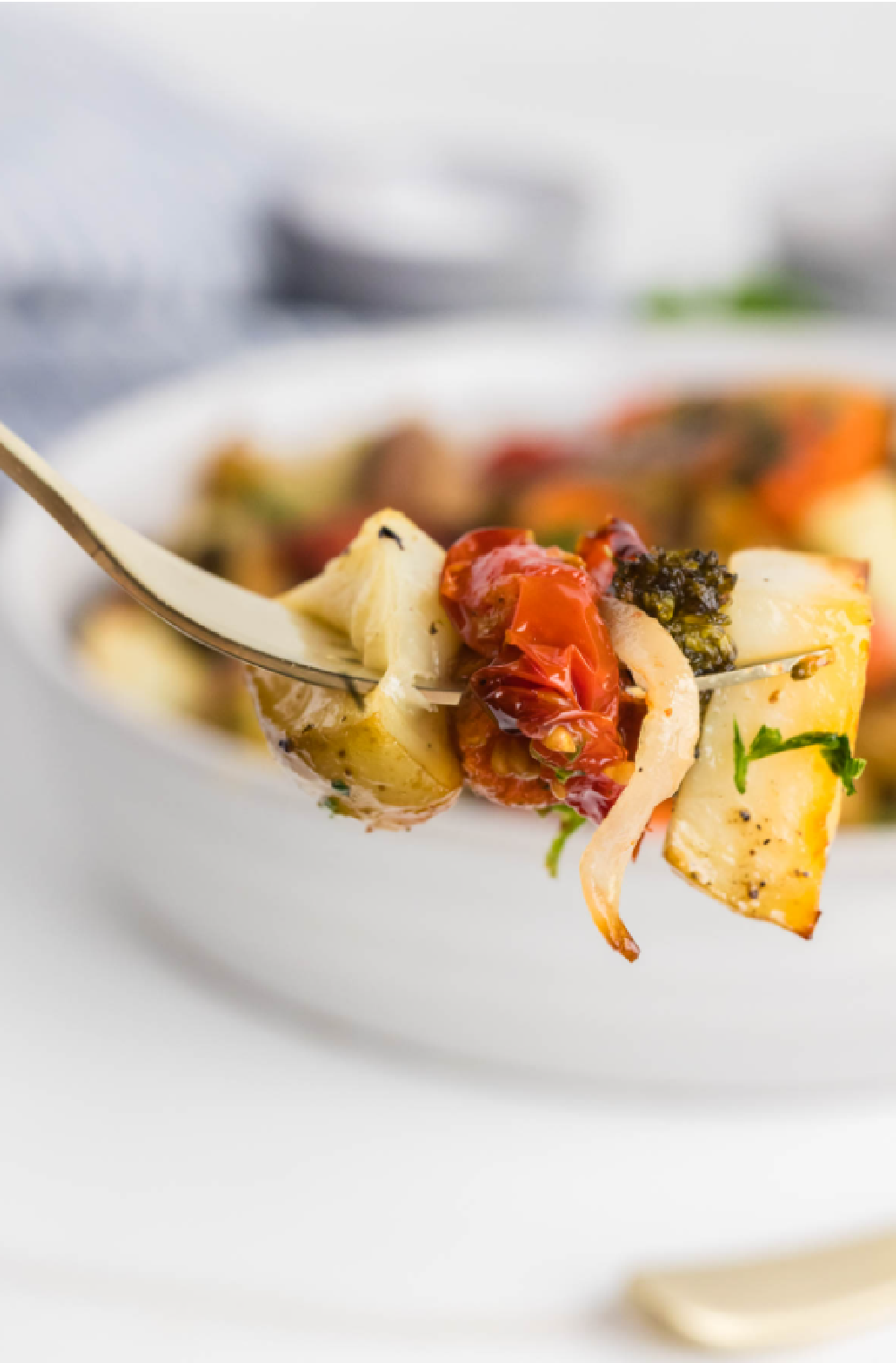 roasted potatoes, onion, tomatoes on a fork