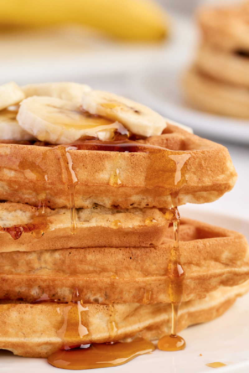 a pile of homemade banana waffles with sliced banana on top
