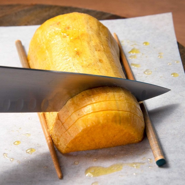 using chopsticks on either side of a butternut squash to make even cuts