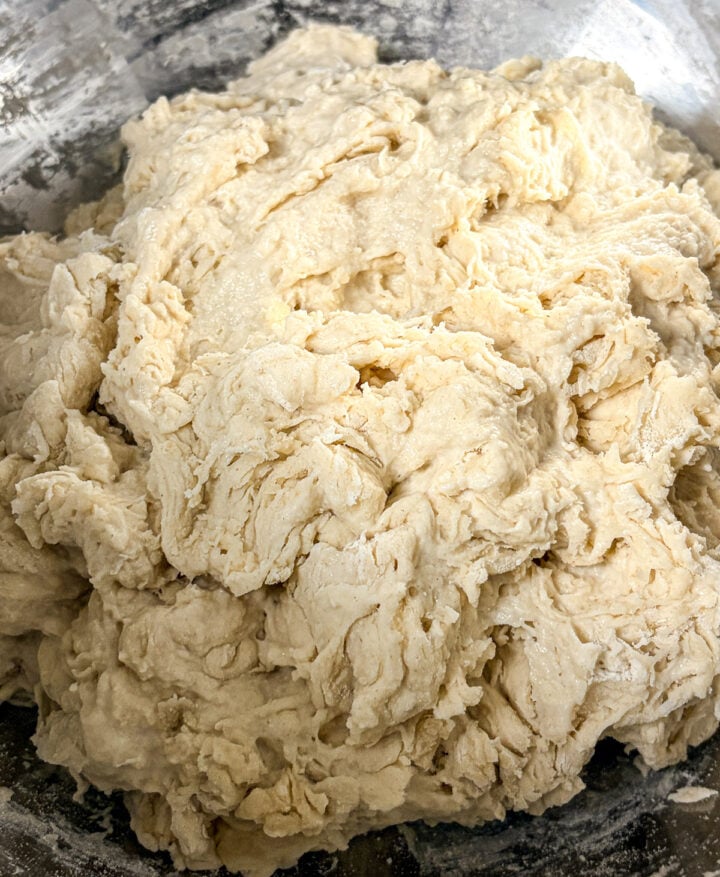 Shaggy sourdough dough mixed in a stainless steel bowl.